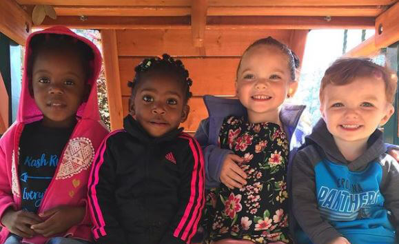 Smiling children sit in a row