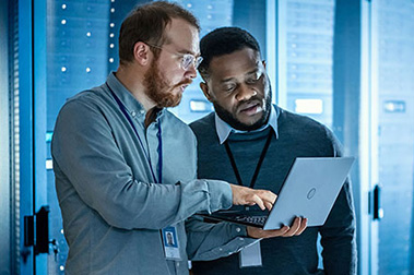Two men with a laptop in a data center