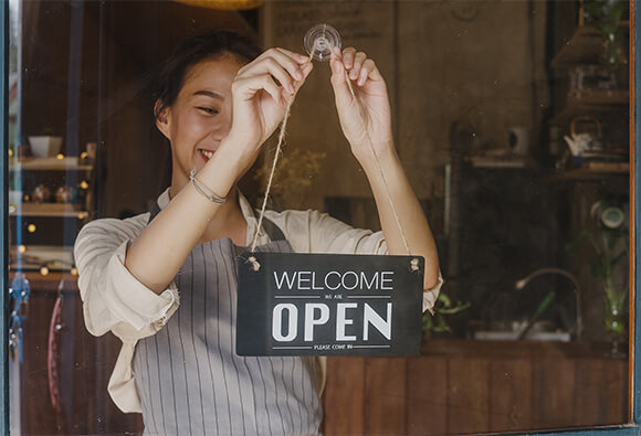 Small Business Owner Placing Open Sign on Window